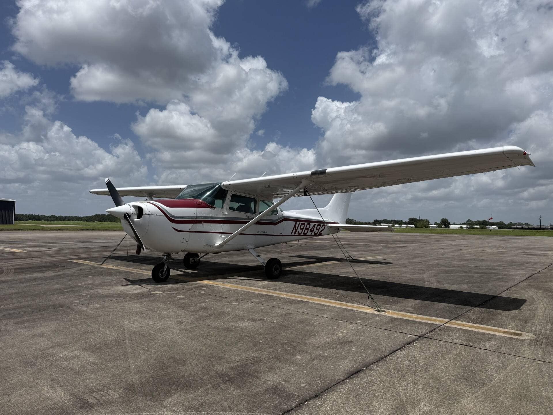 Cessna 172P Skyhawk II N98492 tied down on the ramp under towering cumulus.