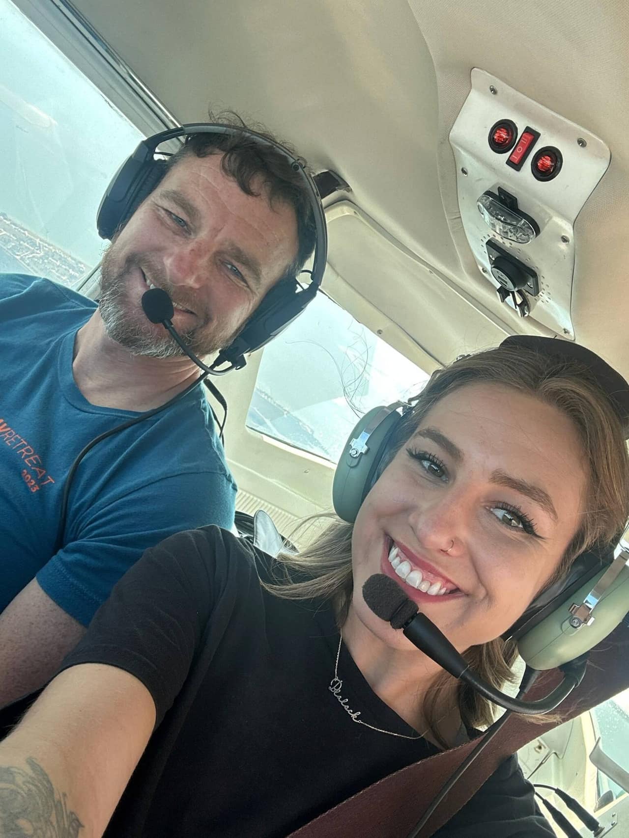 A pilot in a headset flying from the left seat, one hand on the yoke and a moving map clipped to the window post.